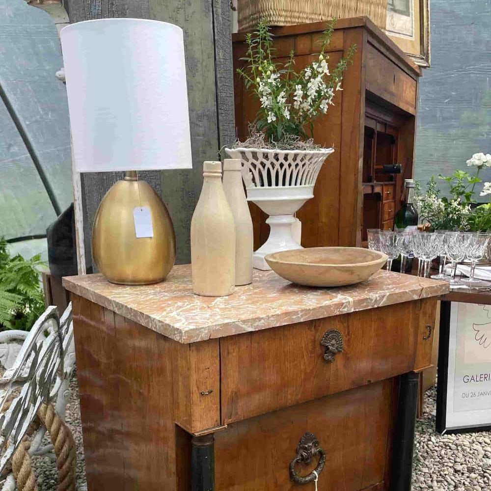 Decorative items on a wooden table with a lamp, bottles, and a bowl.