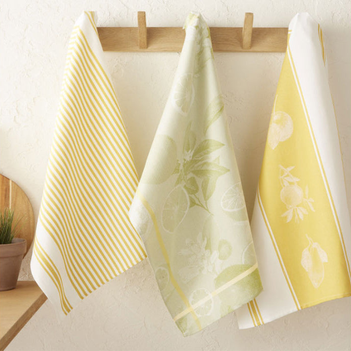 Three towels with different patterns hanging on a wooden rack against a light background.