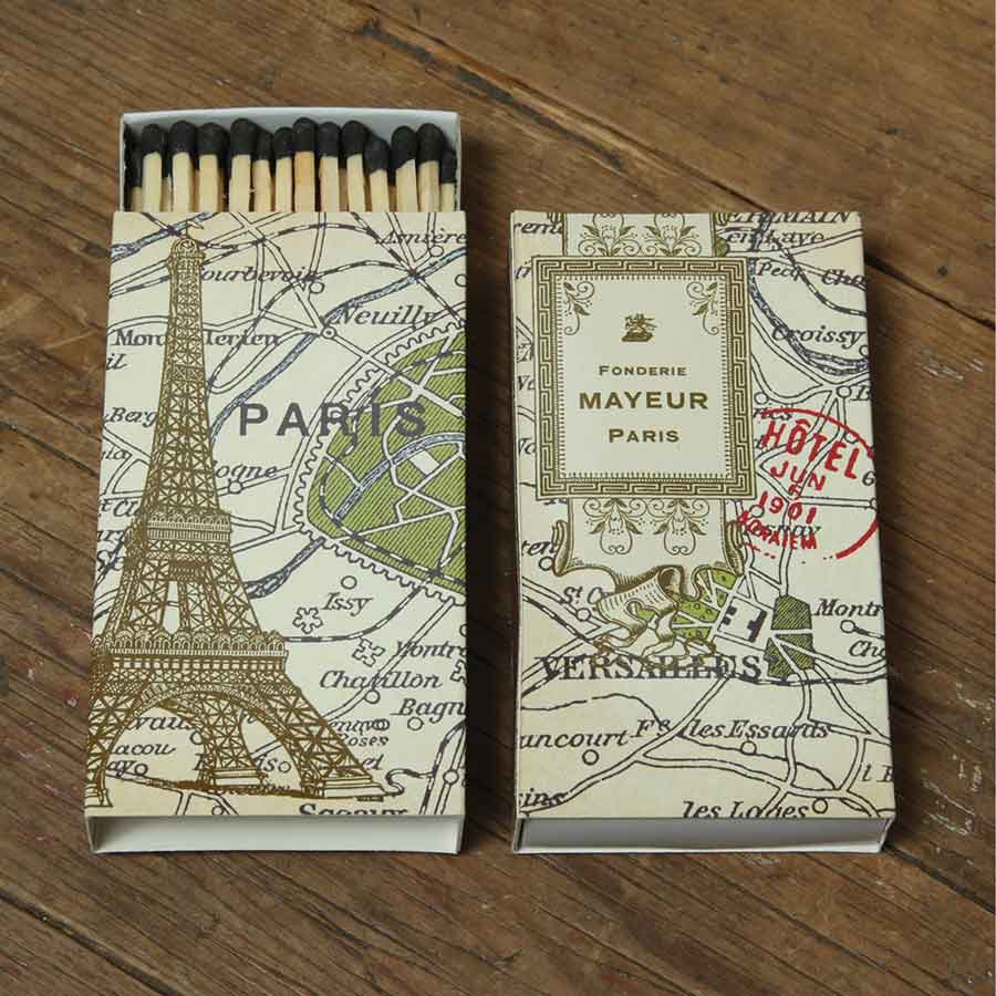 Two matchboxes with Paris-themed designs on a wooden surface