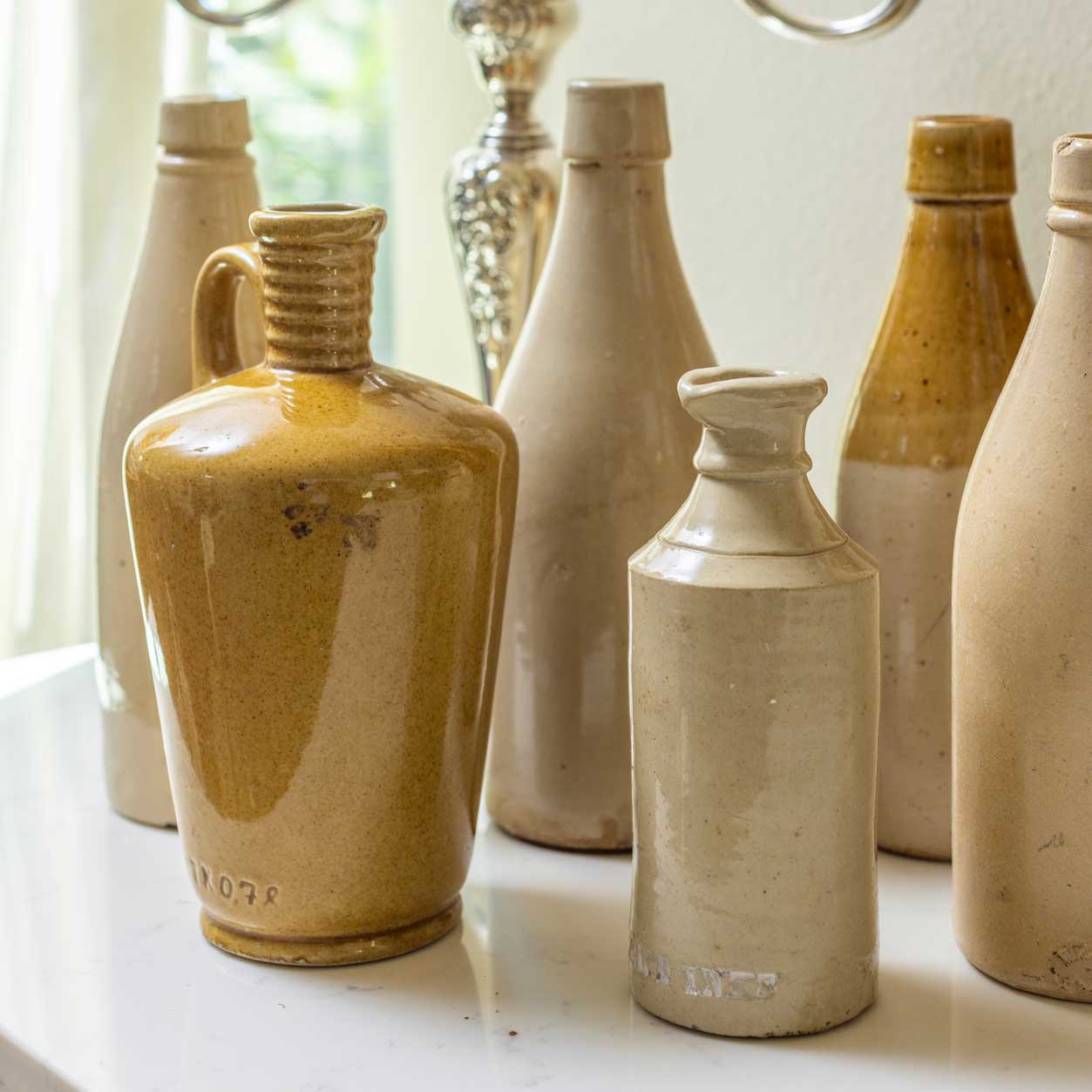 Collection of ceramic bottles with varying designs on a light surface.