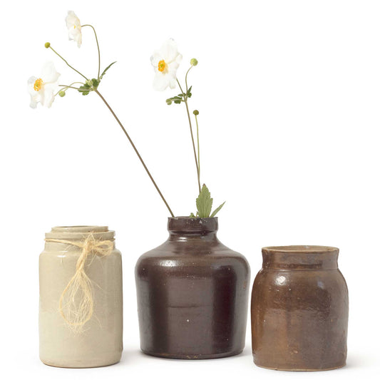 Three ceramic jars with flowers on a white background