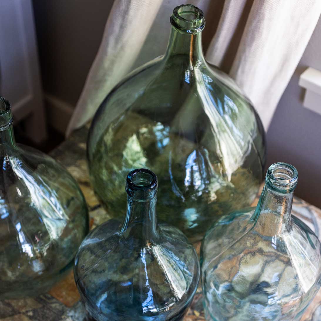 Four green glass bottles on a surface with a neutral background