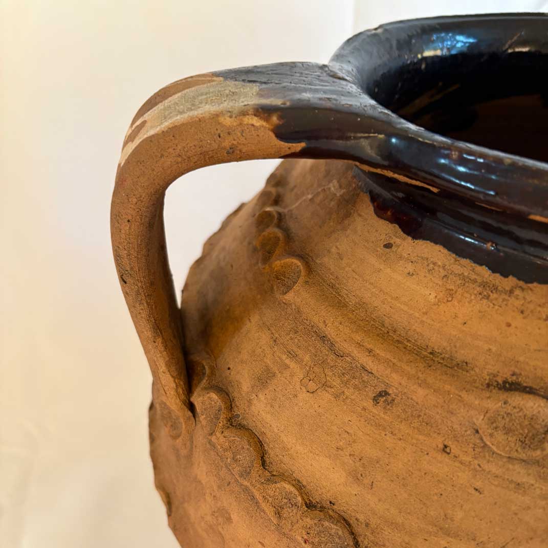 Close-up of a ceramic pot with a handle on a plain background