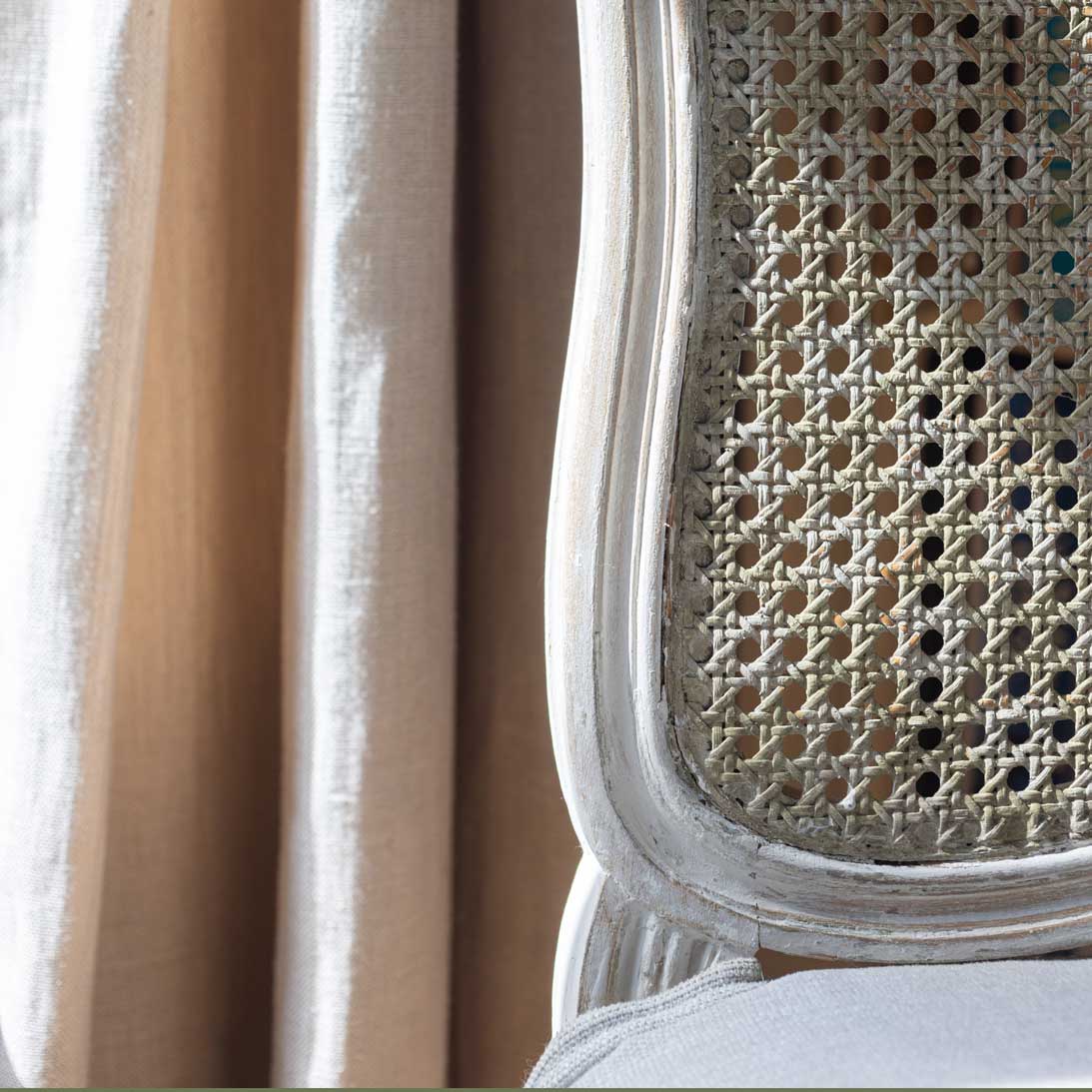 Close-up of a wicker chair backrest with a neutral curtain background