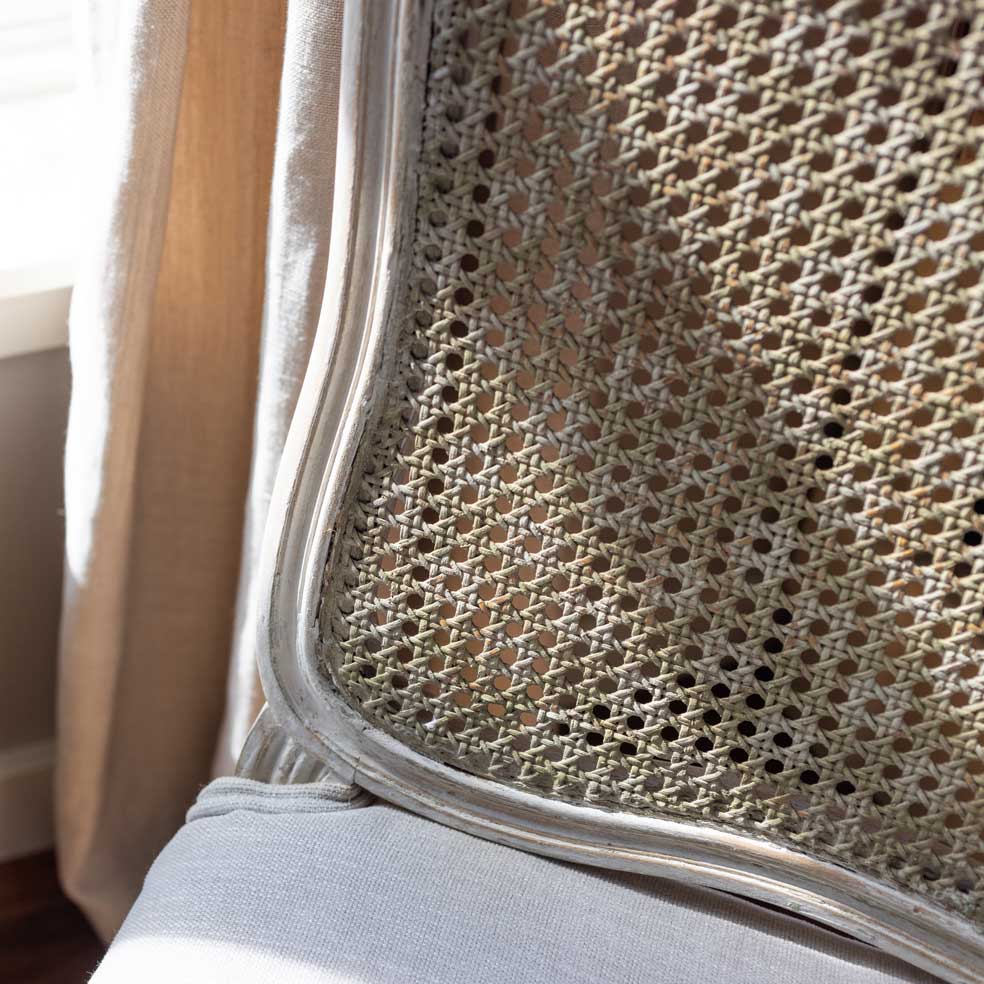 Close-up of a chair with woven backrest and light blue cushion.