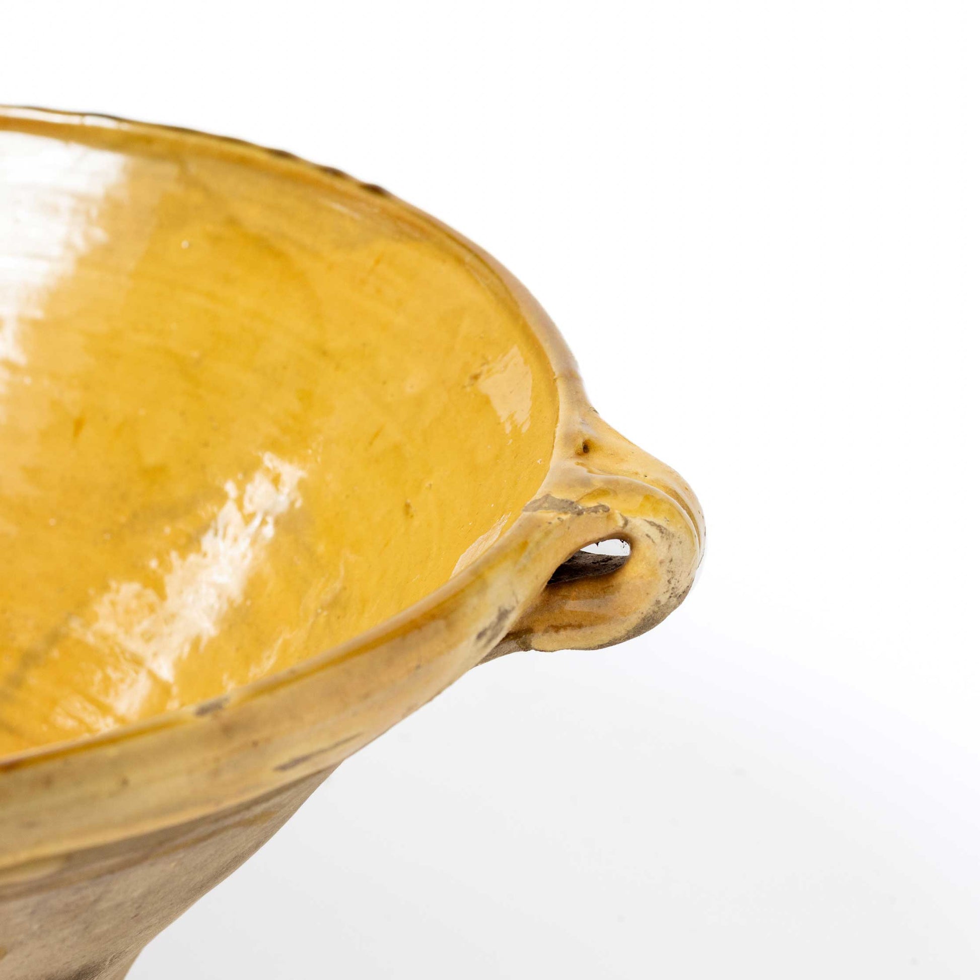 Close-up of a yellow ceramic bowl with a handle on a white background