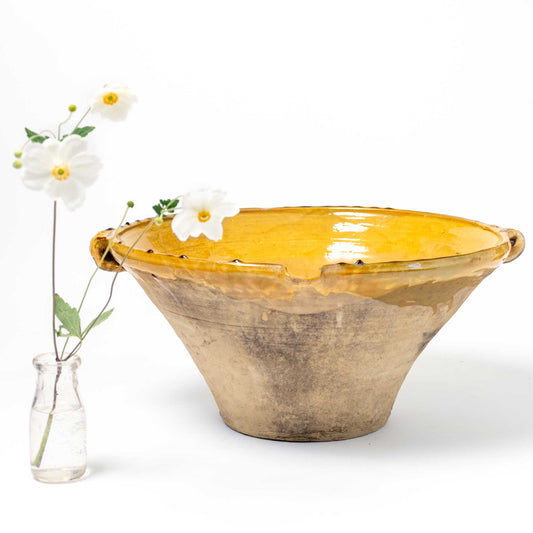 Yellow ceramic bowl with a vase of flowers on a white background