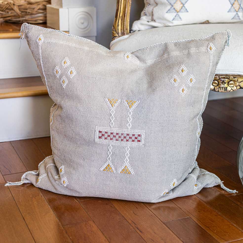 Decorative pillow with geometric patterns on a chair next to a window