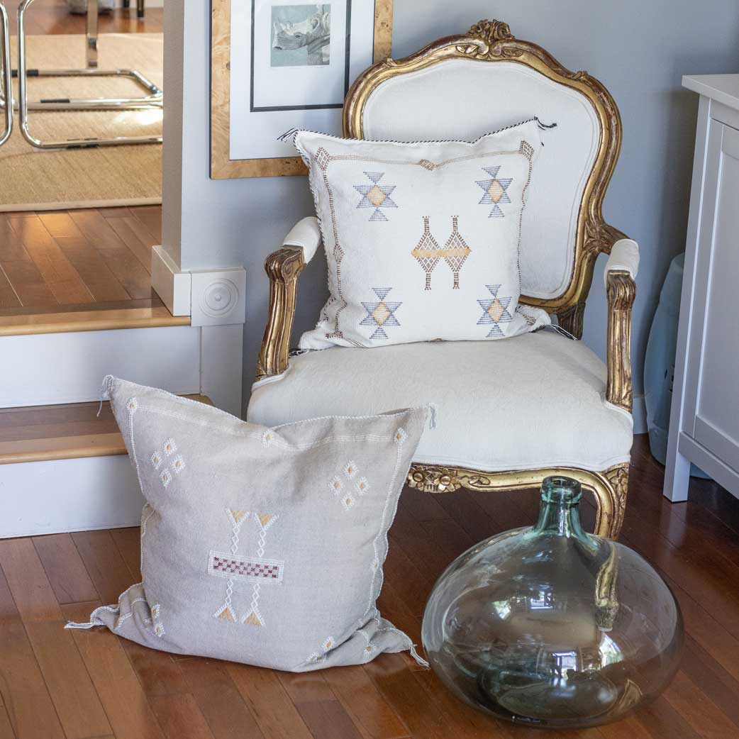 Decorative pillow with geometric patterns on a chair next to a window