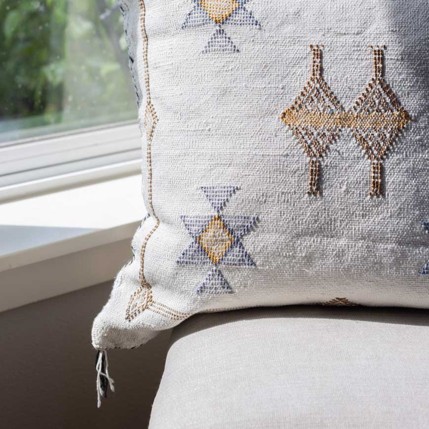 Decorative pillow with geometric patterns on a chair next to a window